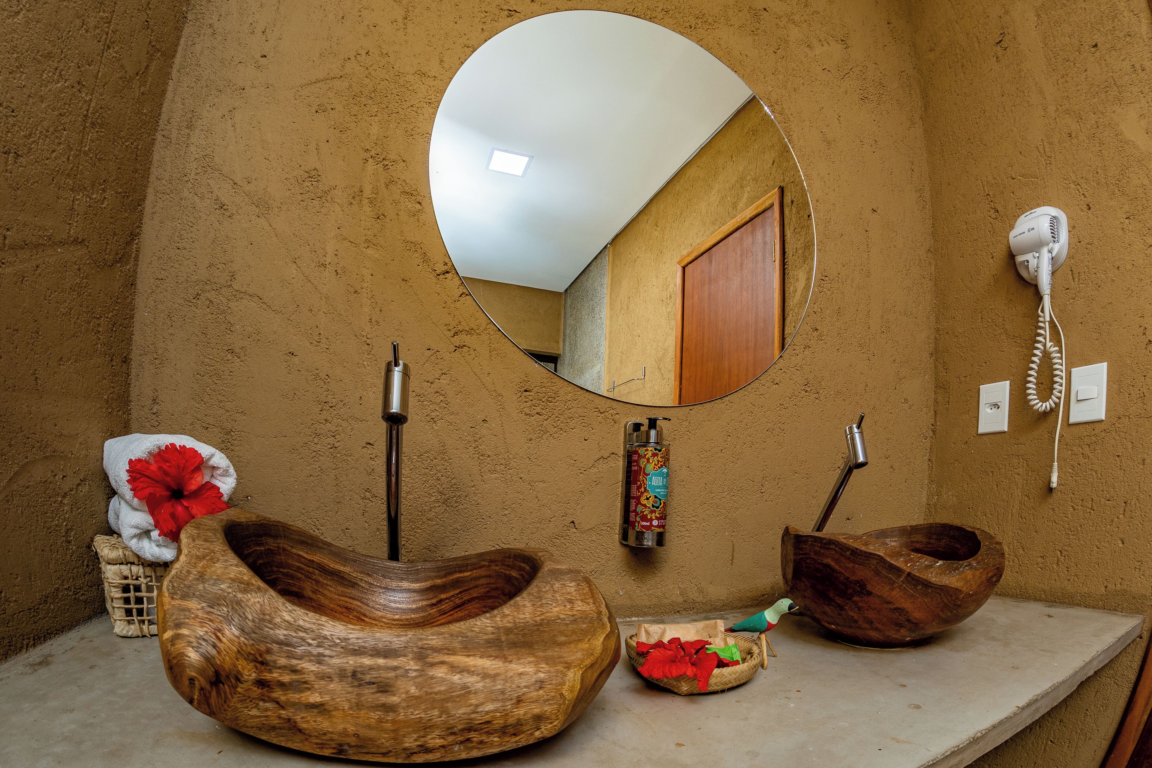 Un baño con un lavabo de madera, un espejo, un secador de pelo y un perchero para toallas.