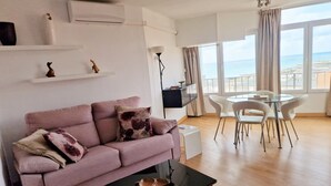 A living room with a sofa, coffee table, and dining area with chairs.