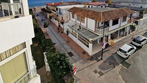 A coastal residential area with buildings, a street, and a view of the sea.