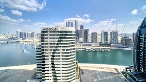 Un immeuble de grande hauteur portant l’inscription « DAMAC », une marina avec des bateaux et, au loin, le profil de la ville.