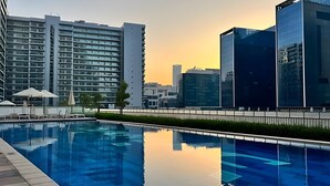 Une piscine offrant une vue dégagée sur les bâtiments modernes qui se dressent à l’arrière-plan.
