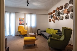A living room with a sofa, two armchairs, a coffee table, and a wall decorated with metal plates. - City Cottage - Kalamata Mediterranean Suites & Villas
 (Kalamata)