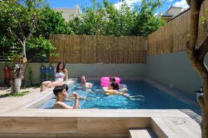 A swimming pool with people relaxing and floating. - City Cottage - Kalamata Mediterranean Suites & Villas
 (Kalamata)