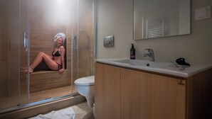 Un baño con cabina de ducha, inodoro y lavabo con espejo superior.