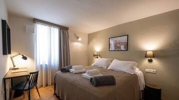 Hotellihuone, jossa on sänky, työpöytä, tuoli ja ikkuna, jossa on verhot.