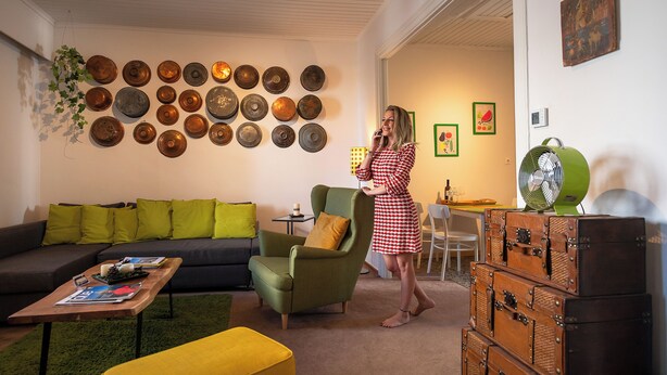 Una sala de estar con sofá, sillón, mesa de centro y decoración en la pared.