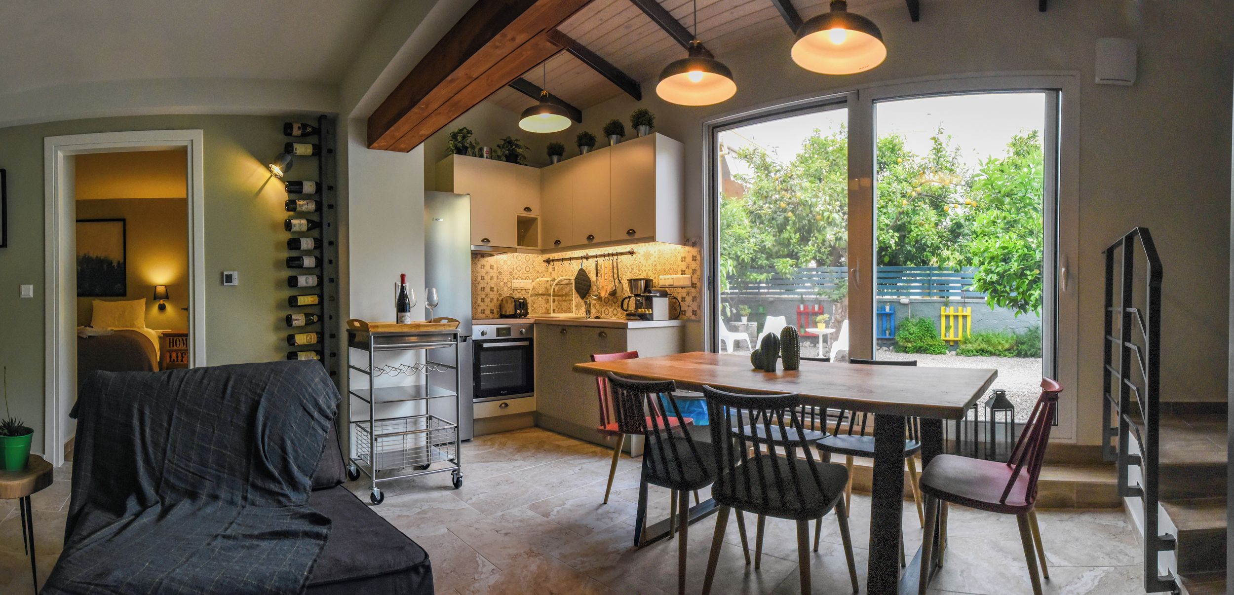 A modern kitchen with a dining area, large windows, and a cozy seating area.
