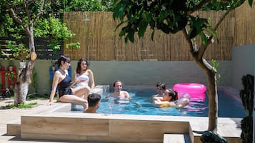 Ein Poolbereich mit Bambuszaun, Topfpflanzen und einer Holzterrasse.
