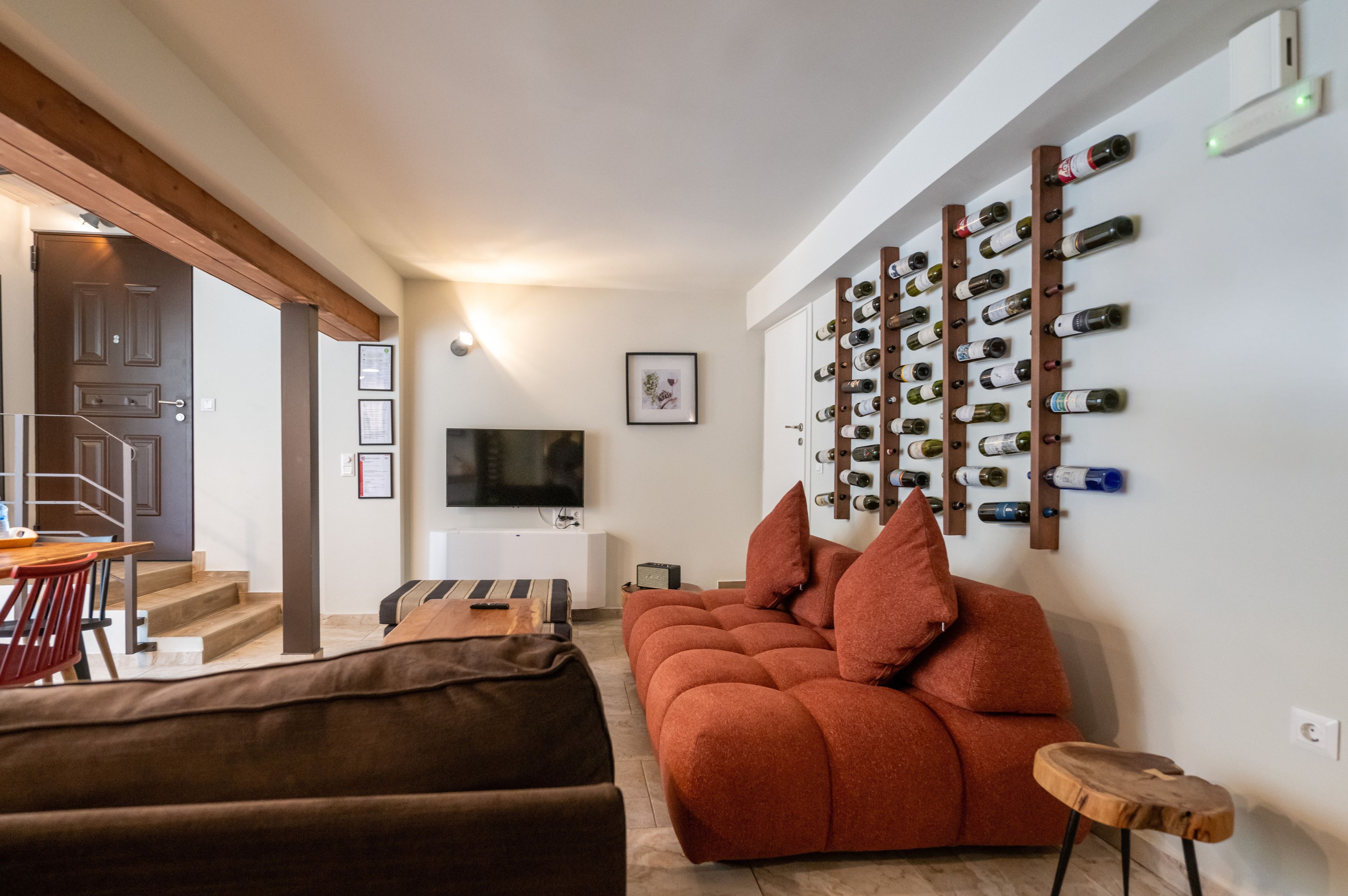 A modern living room with a sofa, a coffee table, a TV, and a wine rack on the wall.