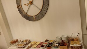 A buffet table with various food items and a decorative wall clock.