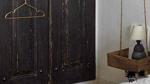 A dark wooden door with four metal hangers and a small wooden box with a lamp.