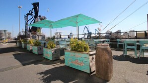 Outdoor seating with umbrellas, wooden planters with greenery, and a sign for 'Do Viney's Cocktails'.