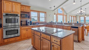 A spacious kitchen with wooden cabinets, stainless steel appliances, and a large island. - Premier Soundfront Dog Friendly Oasis w/ Pool, Hot Tub, Elevator, and Much More! (Avon)