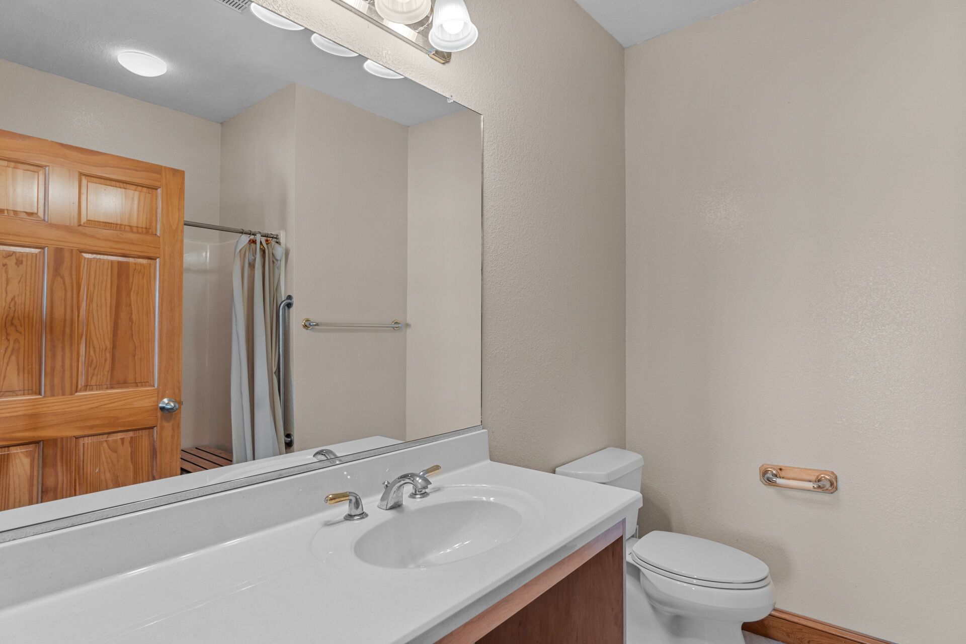 Une salle de bain avec un lavabo blanc, des toilettes et une porte en bois.