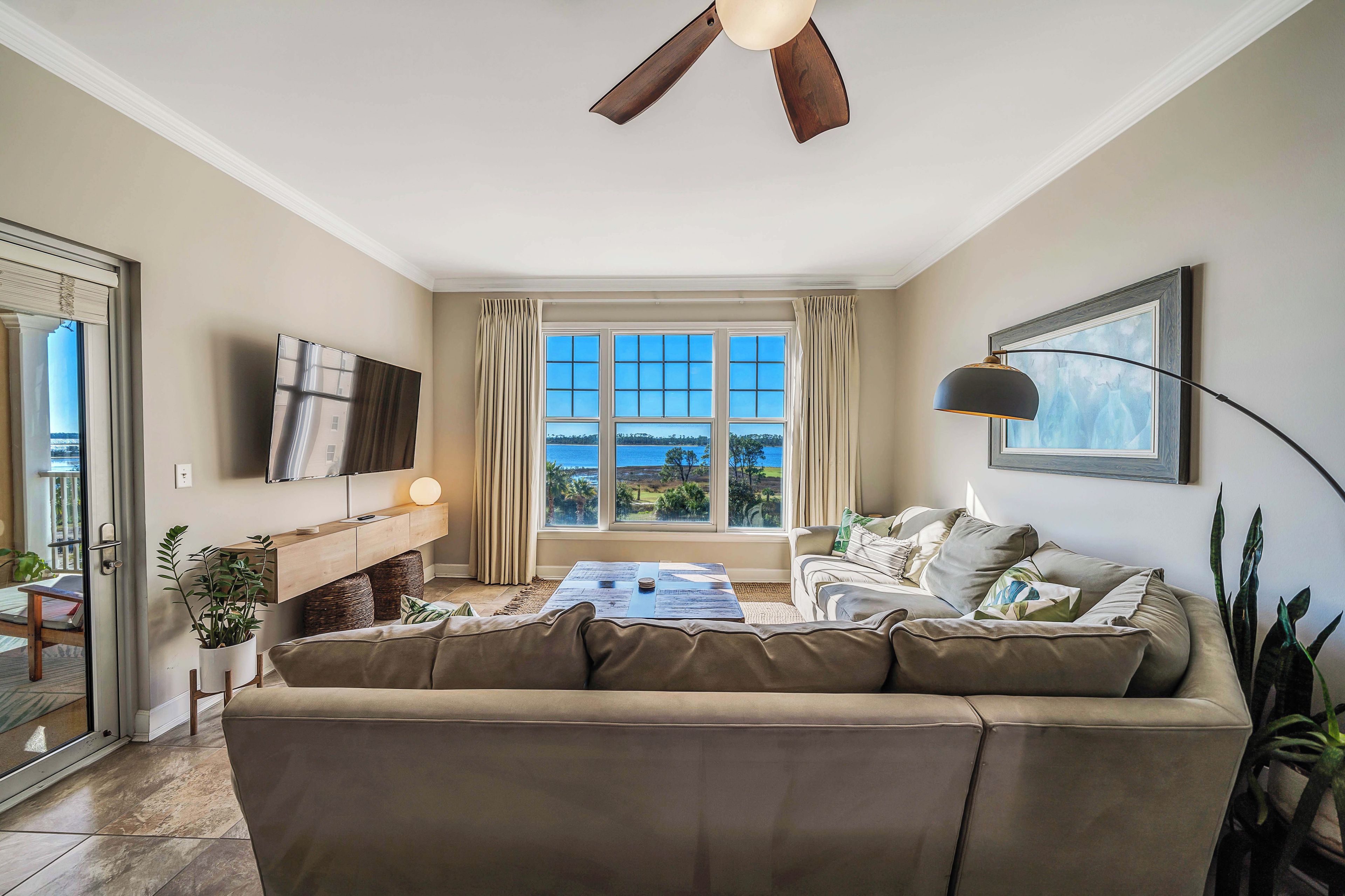 A living room with a large window, a ceiling fan, a flat-screen TV, a sofa, and a coffee table.