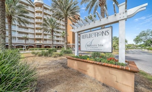 Naamplaatje voor Reflections Serenity Spa bij Bay Point, met een meerlaags gebouw met balkons en palmbomen.