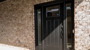 A brick building with a dark-colored door and a small window above it. - Modern 4BR Oasis - Main Level Master + 2 King Beds (Forest)