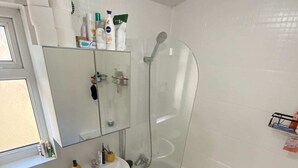 Baño con inodoro, lavamanos, espejo y ducha.