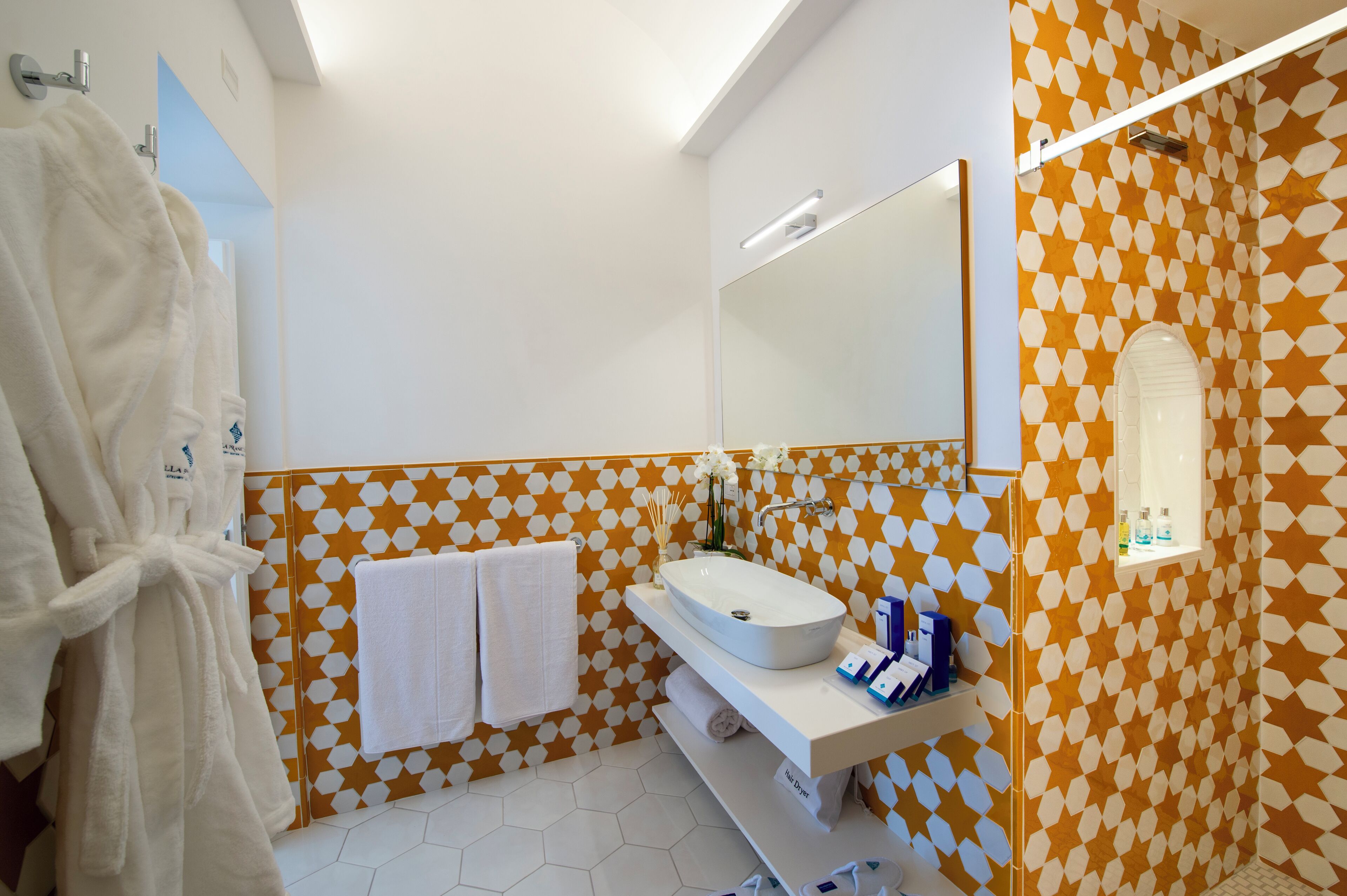 A bathroom with a white sink, mirror, and patterned walls.