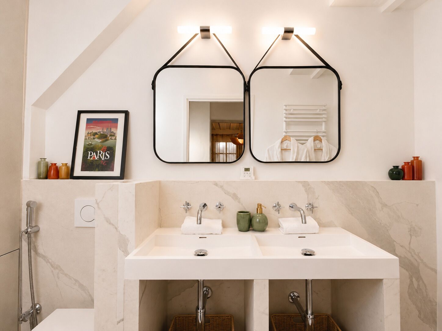 A bathroom with two mirrors, a framed picture, and a shower.