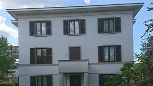 Een gebouw met twee verdiepingen, een symmetrische gevel, grote ramen en een centrale ingang.