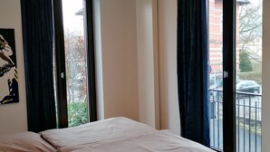 Een slaapkamer met een bed, een plafondlamp en een raam met gordijnen.