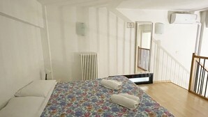 Une chambre à coucher avec un lit, un radiateur, un miroir et un escalier.