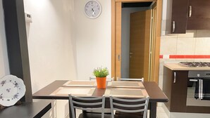 Une cuisine compacte avec un coin repas, comprenant une horloge, une plante en pot et une cuisinière.