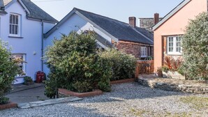 A residential area with houses, gravel paths, and a variety of plants. - The Tack Room, shared hot tub and sauna (Hartland)