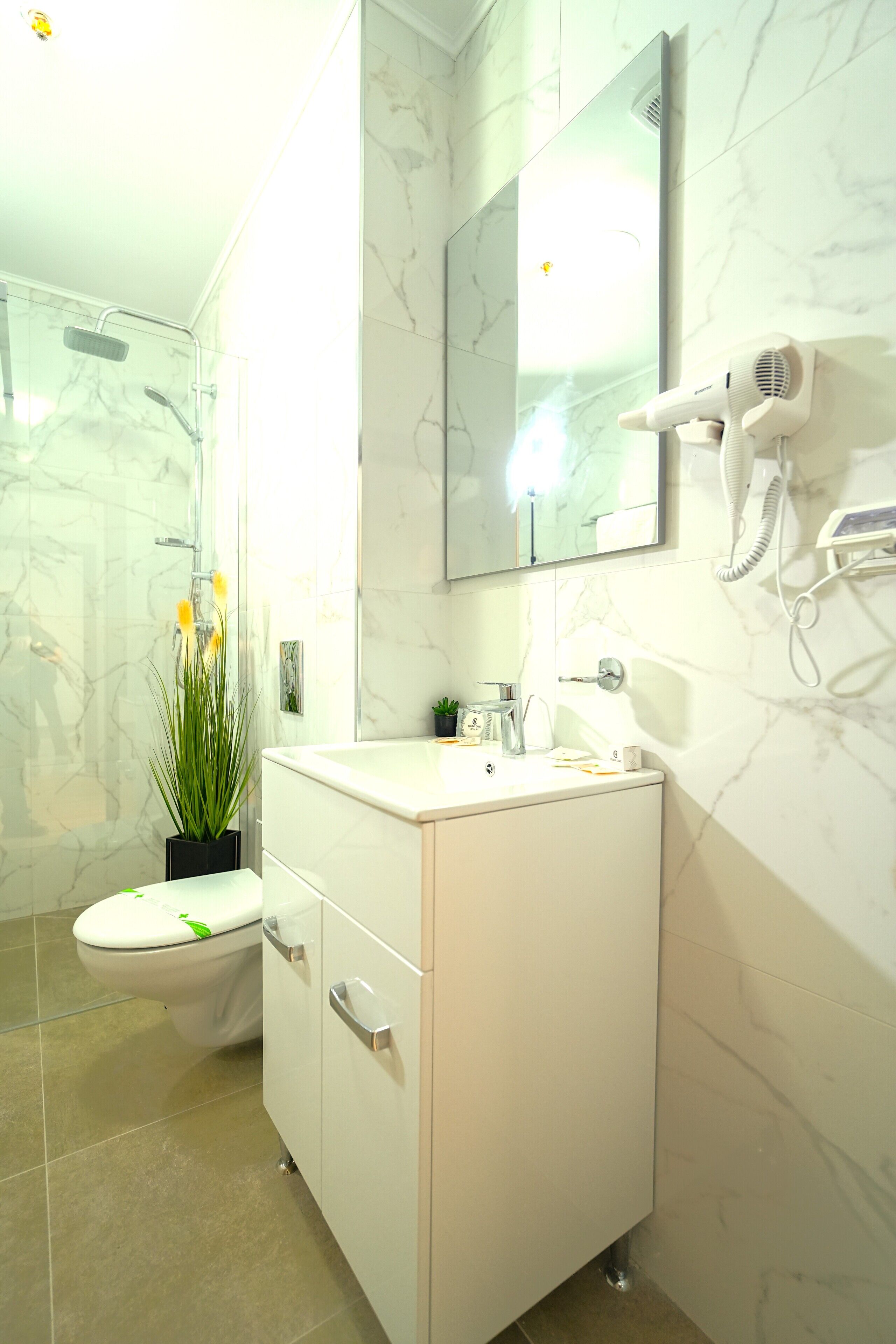 Een badkamer met toilet, wastafel en een aan de muur bevestigde haardroger.