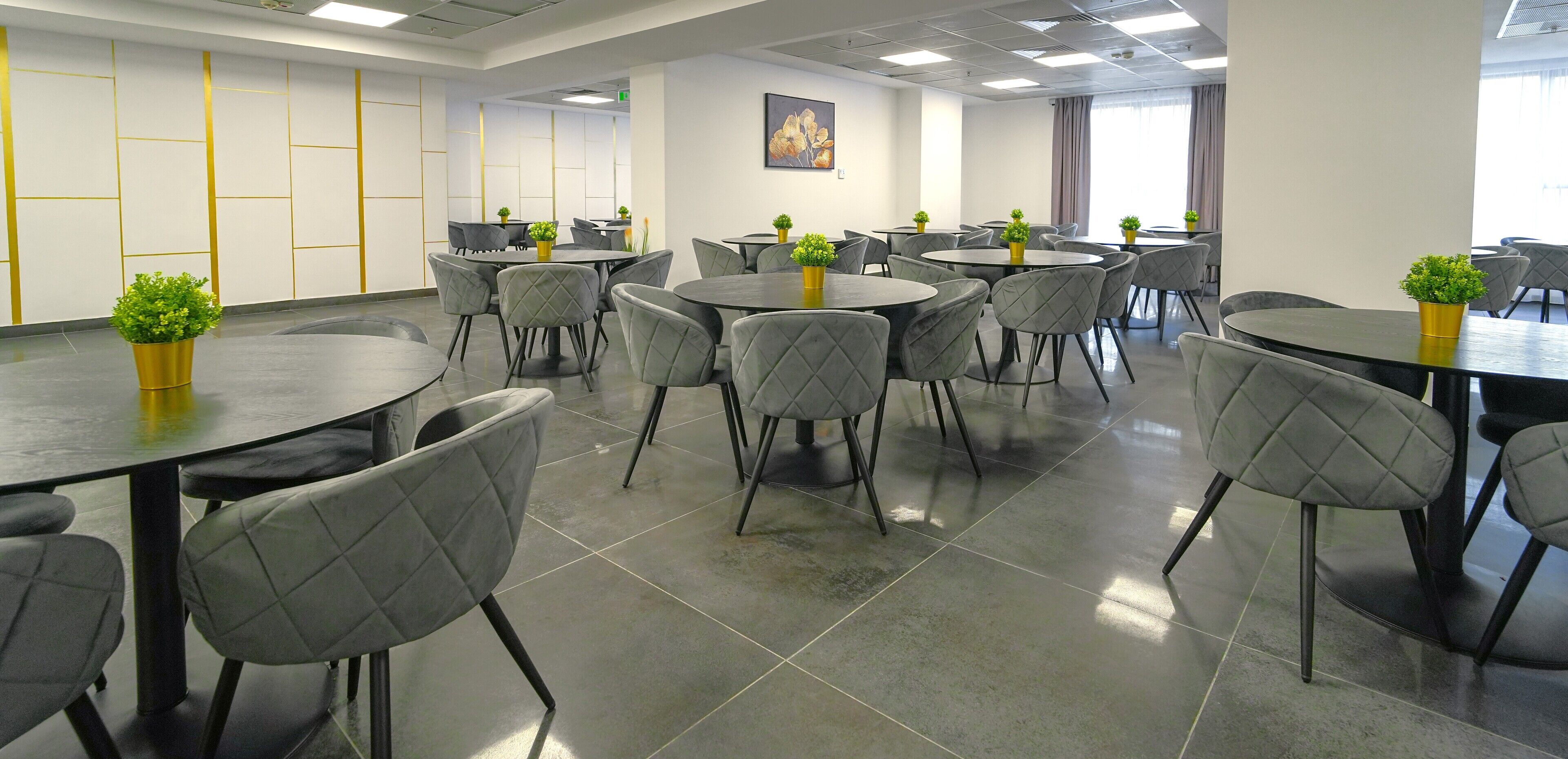 Un salón de conferencias con varias mesas y sillas, cada una con una pequeña planta encima.