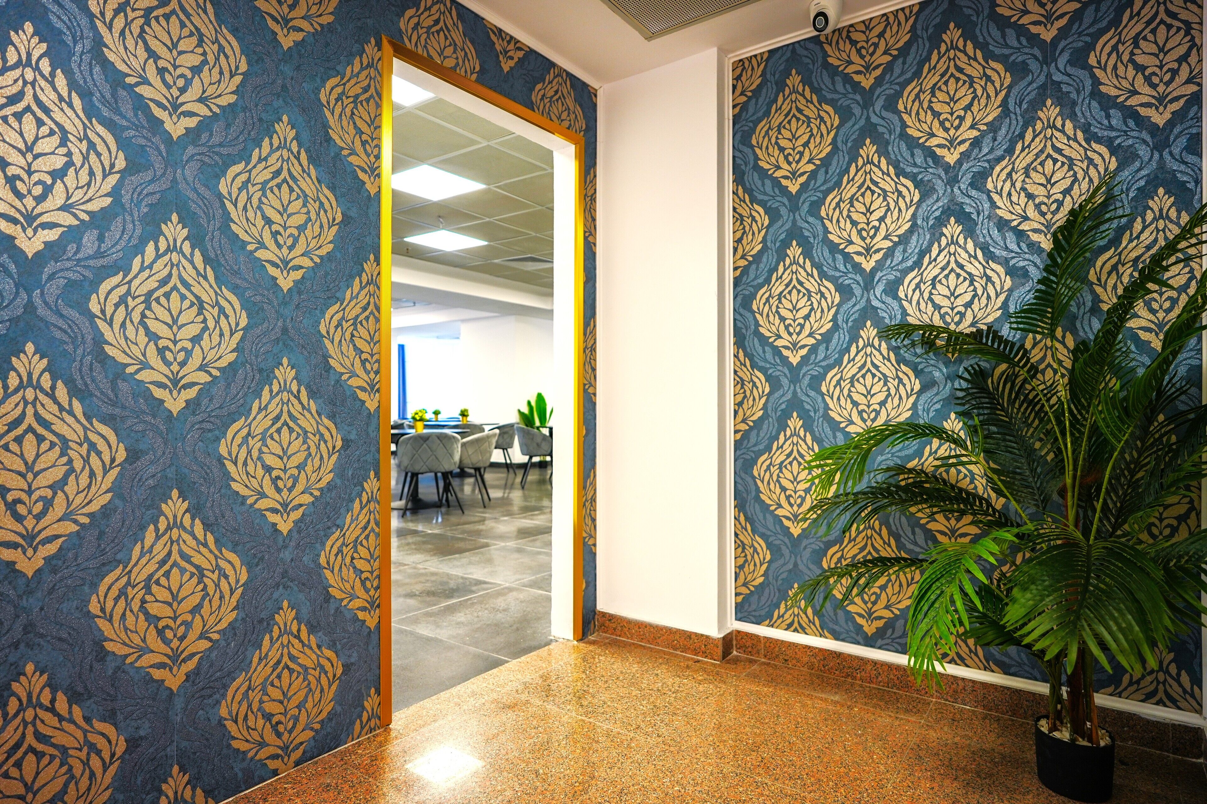A hallway with patterned wallpaper and a potted plant.