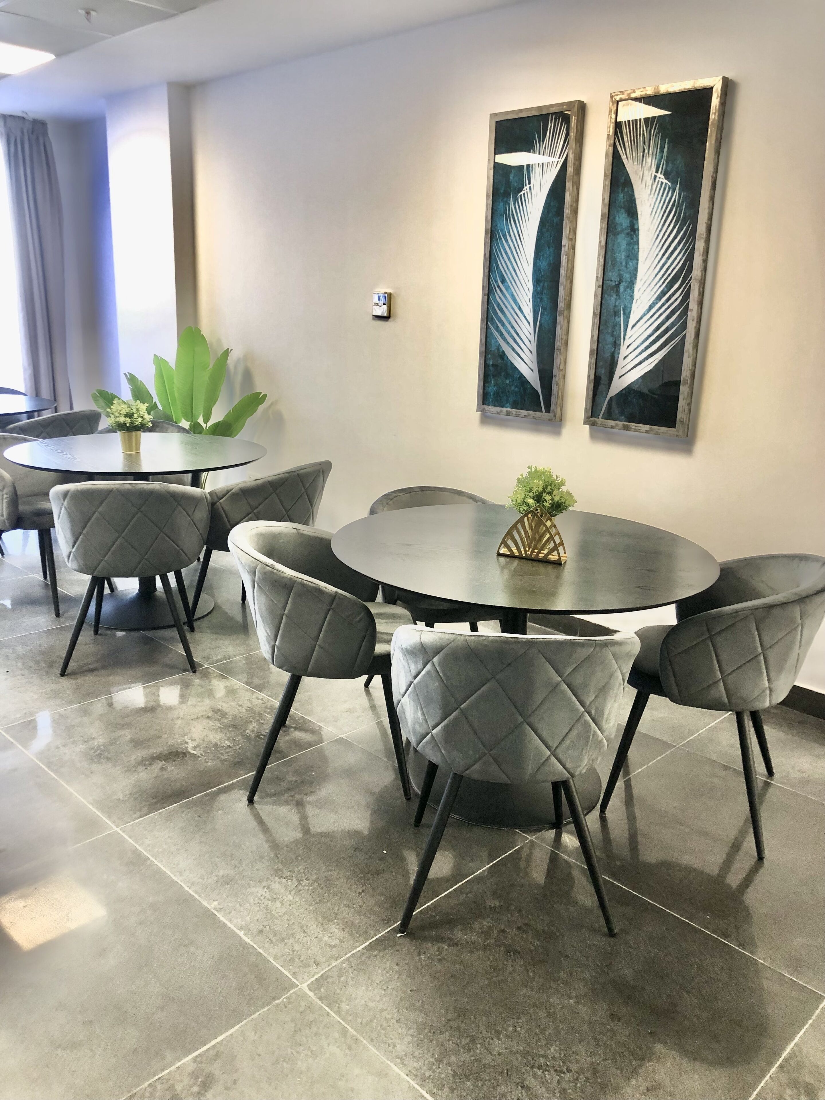 Sala de conferências com uma mesa redonda, seis cadeiras e duas obras de arte fixadas nas paredes.