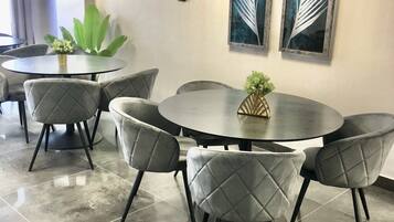 Sala de conferências com uma mesa redonda, seis cadeiras e duas obras de arte fixadas nas paredes.
