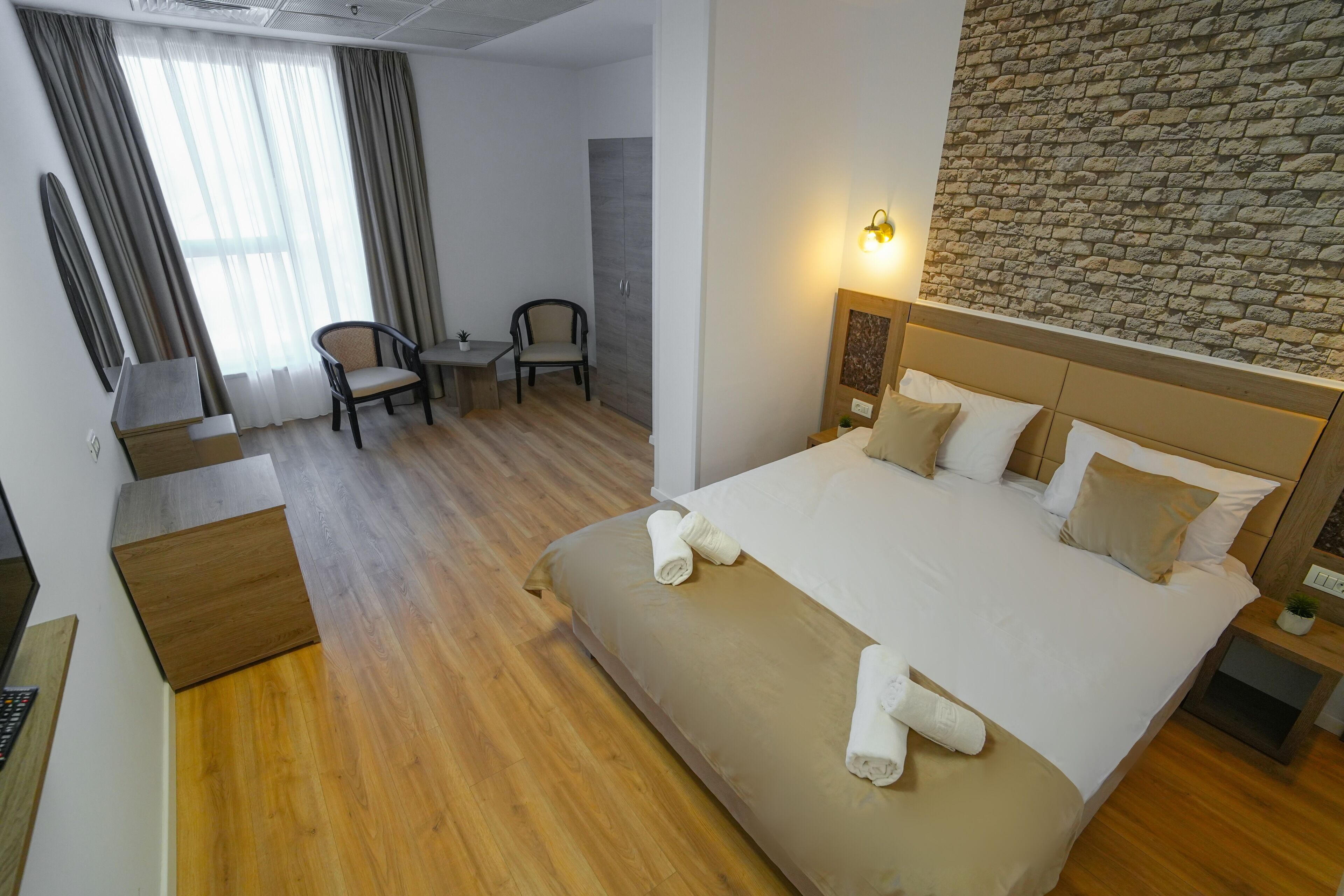 Une chambre d’hôtel avec un grand lit, un bureau, deux chaises et un mur en pierre.