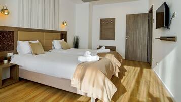 Una habitación de hotel con una cama grande, mesitas de noche, un televisor y una puerta de madera.