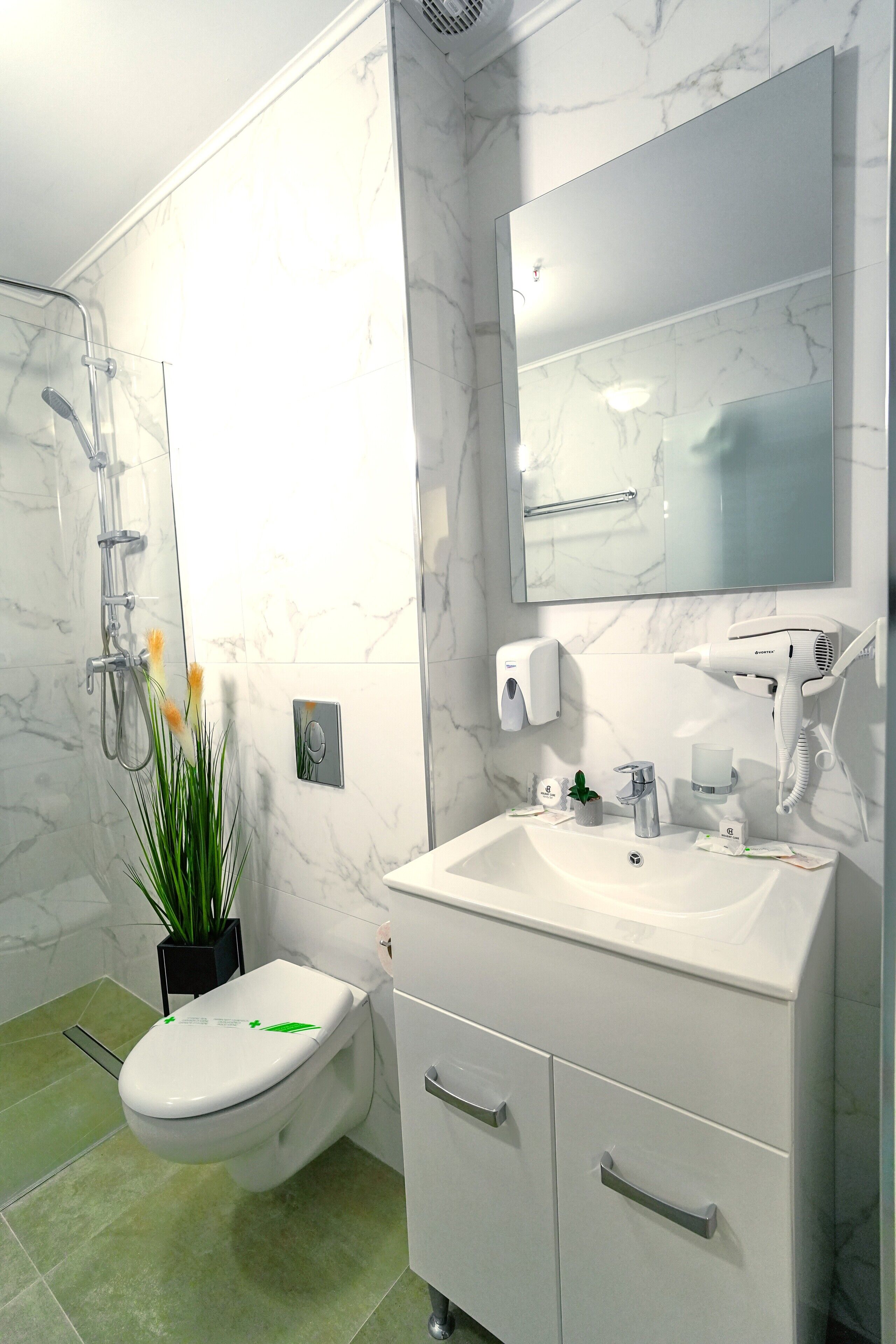 A modern bathroom with a white sink, mirror, and toilet.
