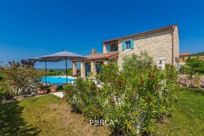 Enjoy a pool and sea views from this villa's outdoor seating area surrounded by lush greenery.