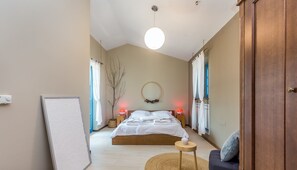 Relax in a spacious bedroom with a large bed, bedside tables, and a round mirror.