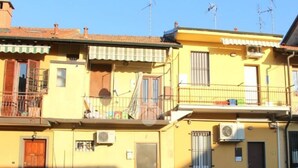 A yellow building with a balcony, a door, and an air conditioning unit. - Cornaredo apartment 10 minutes from Milan (Cornaredo)
