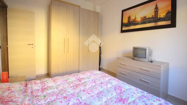A bedroom with a bed, a wardrobe, a dresser, and a painting of a cityscape. - Cornaredo apartment 10 minutes from Milan (Cornaredo)