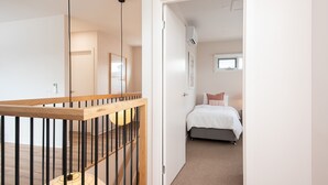 A bedroom with a bed, a window, and a staircase with a wooden railing.