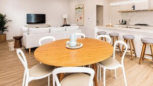 A modern living room with a sofa, TV, and a dining area with a table and chairs.