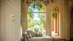 A room with a sofa facing a large arched window, a zebra-patterned rug, and a decorative ceiling. - Villa Tounsi - Five Bedroom Villa, Sleeps 10 (Douar Tounsi)