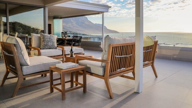 Un área de estar moderna al aire libre con mobiliario de madera y vista al océano.