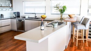 Una cocina moderna con una isla central, electrodomésticos de acero inoxidable y un área de comedor con taburetes de bar.