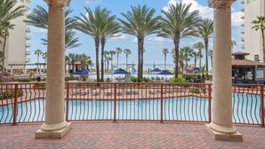 A pool area with palm trees, a pool, and a building in the background.