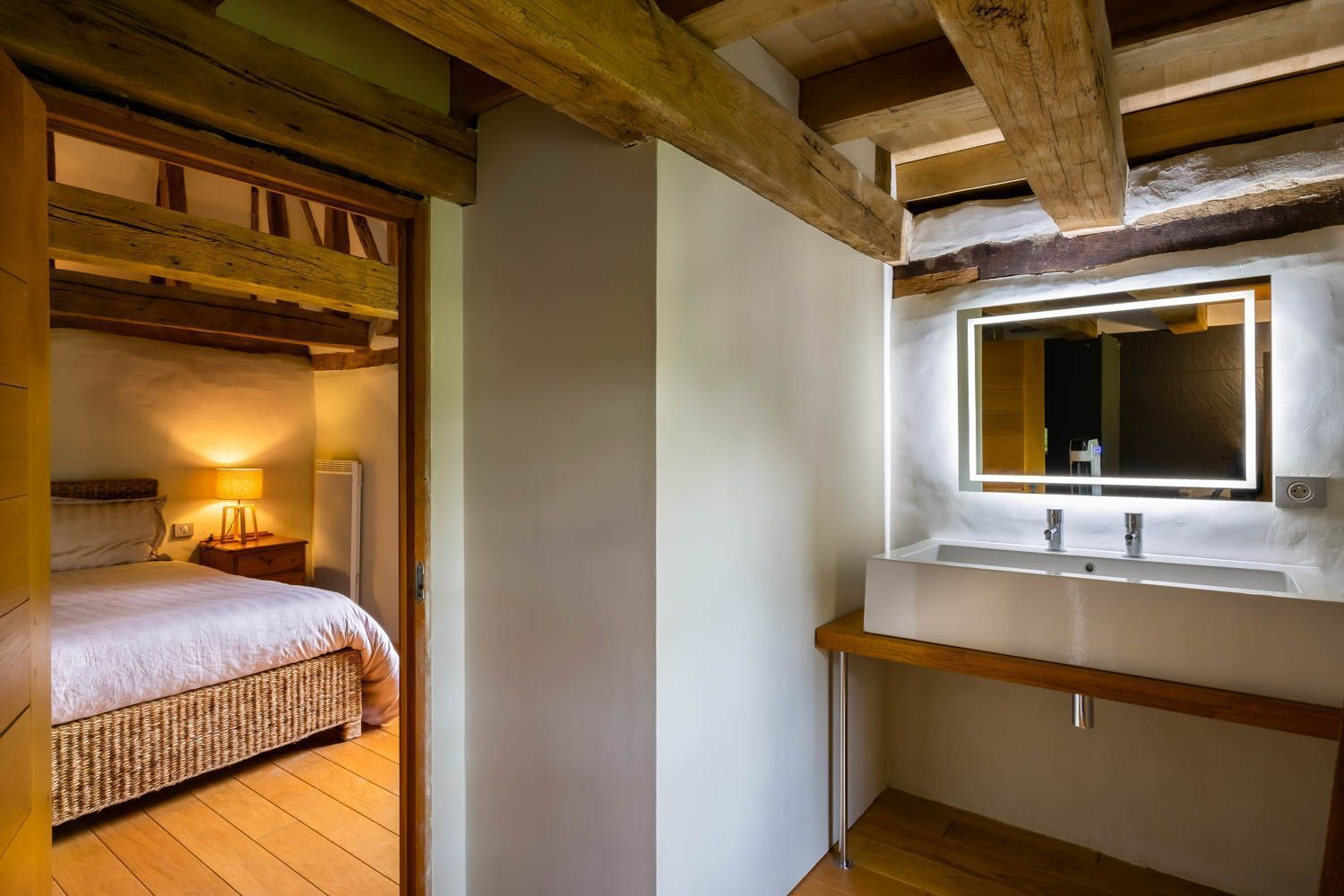 A bedroom with a bed, bedside lamp, and a small bedside table.