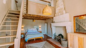 Een slaapkamer met een bed, een open haard, een trap en een hanglamp.