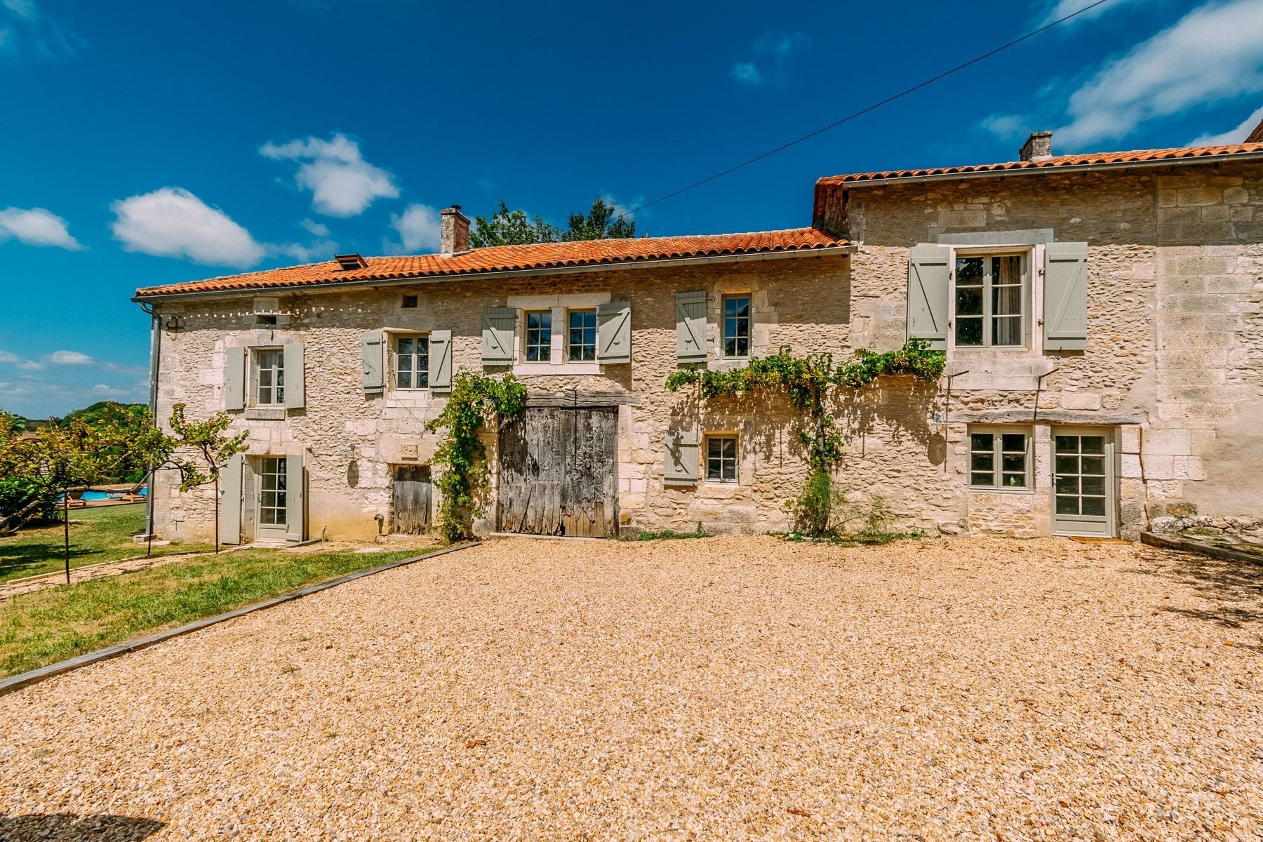 Edificio de piedra con camino de entrada de grava y una puerta de madera.